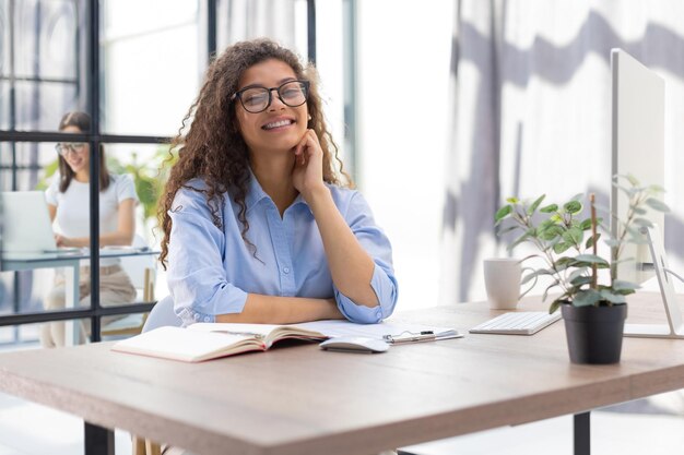 Une femme d'affaires souriante regardant la caméra faire une conférence ou un appel d'affaires enregistrant un blog vidéo parlant avec le client Le collègue est en arrière-plan