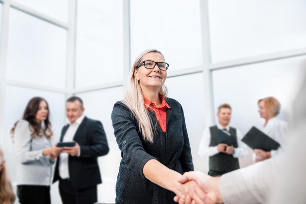 Femme d'affaires souriante, serrant la main de son partenaire commercial