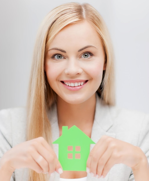 femme d'affaires souriante avec le symbole de la maison écologique verte