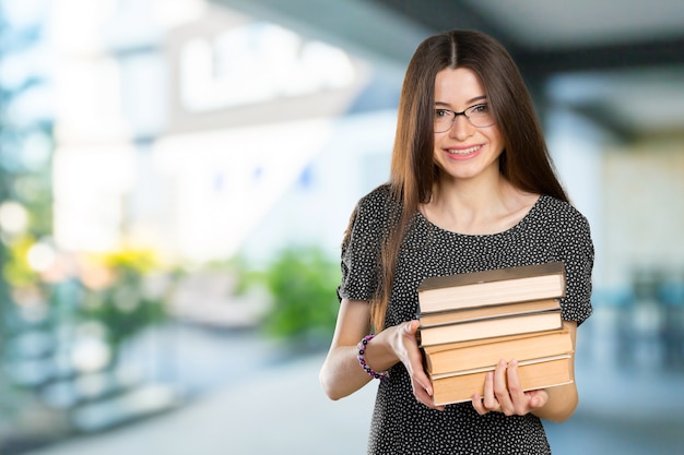 Femme d'affaires souriante tenant une pile de livres