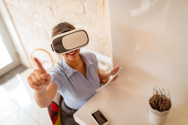 Femme d'affaires souriante utilisant des lunettes de réalité virtuelle dans un café.