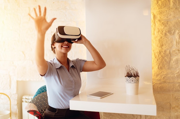 Femme d'affaires souriante utilisant des lunettes de réalité virtuelle dans un café.