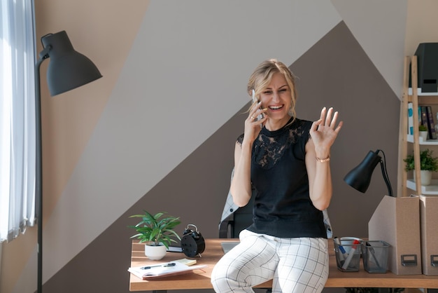 Femme d'affaires souriante utilisant un téléphone au bureau