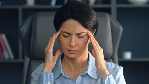 Une femme d'affaires stressée souffrant de maux de tête au travail