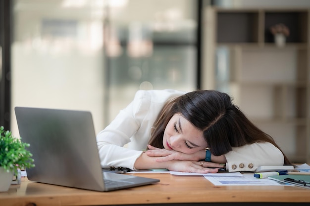 Une femme d'affaires stressée et surmenée se repose sur un bureau dans un bureau.