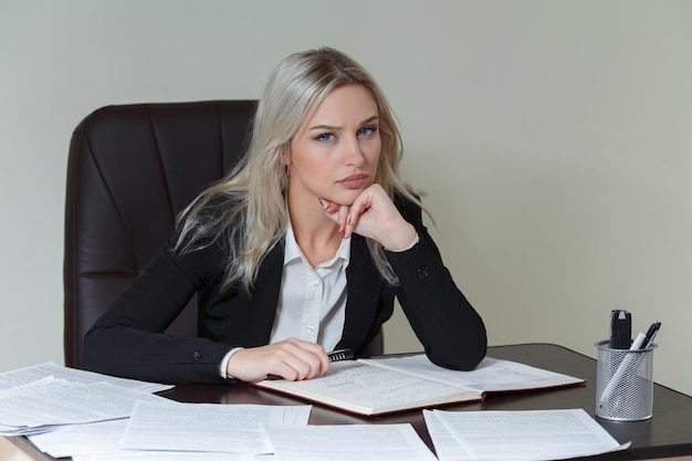 Femme d'affaires stricte en costume assis à la table avec des documents