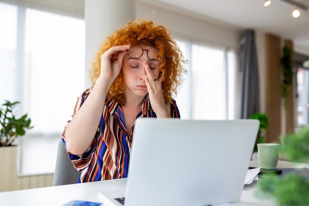 Femme d'affaires surmenée éprouvant de la fatigue au travail alors qu'elle était assise devant un ordinateur portable