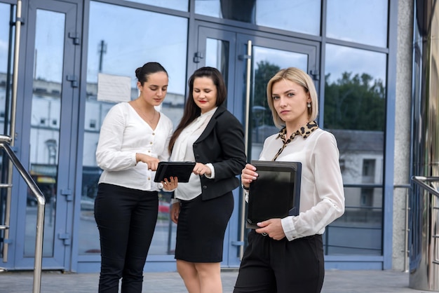 Femme d'affaires avec tablette debout devant ses collègues qui discutent de certaines informations
