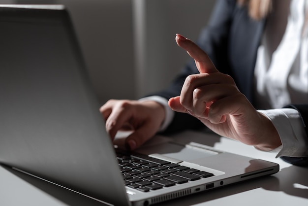 Une femme d'affaires tapant des mises à jour récentes sur un clavier d'ordinateur portable sur un bureau avec un téléphone portable et pointant des idées importantes