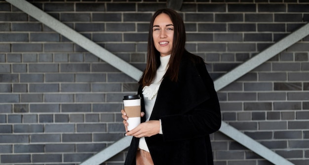 Femme d'affaires avec une tasse de café sur le fond d'un mur de briques