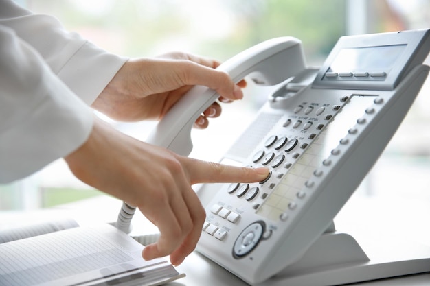 Femme d'affaires avec téléphone IP de bureau