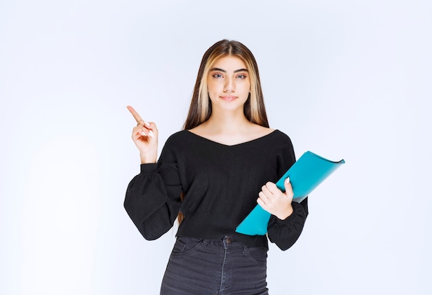 Femme d'affaires tenant un dossier bleu et pointant du doigt son collègue. photo de haute qualité