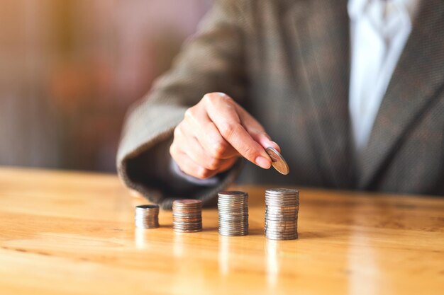 Femme d'affaires tenant et empilant des pièces sur la table pour économiser de l'argent concept