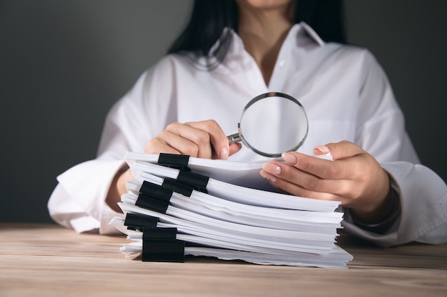 Femme d'affaires tenant une loupe et des documents