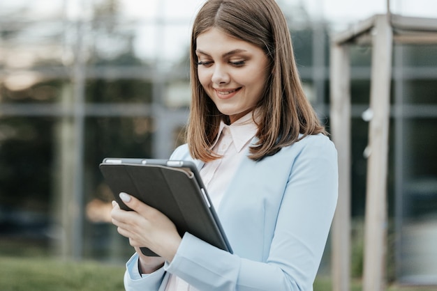 Femme d'affaires tenant une tablette dans les mains à l'aide d'applications professionnelles sur un ordinateur tablette près de l'immeuble de bureaux el