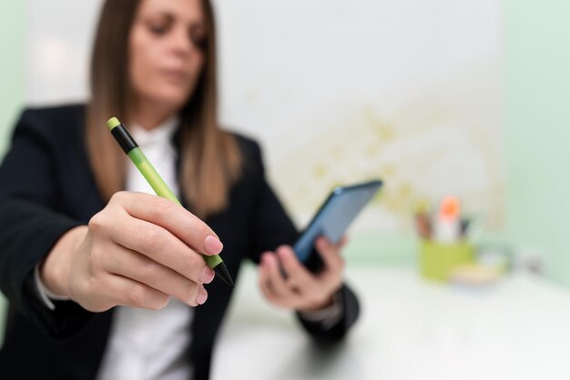 Femme d'affaires tenant une tablette et pointant des informations importantes avec un stylo à la main