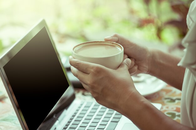 Femme d&#39;affaires tenant une tasse de café et de travailler dans le café