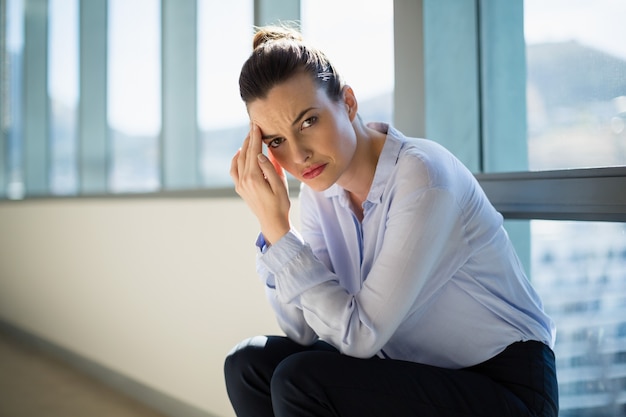 Femme d'affaires tendue assis avec la main sur le front