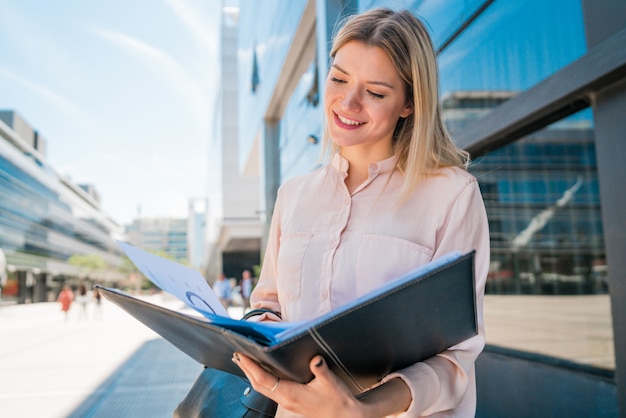 Femme affaires, tenue, presse-papiers, et, debout, dehors