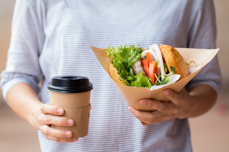 Photo femme d'affaires en train de déjeuner, burger avec un café sur le temps de pause