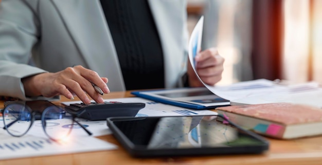 Femme d'affaires travaillant au bureau avec un document sur son bureau faisant de la planification en analysant le concept d'analyse de financement d'investissement de plan d'affaires de rapport financier à l'aide d'une calculatrice et d'un ordinateur portable