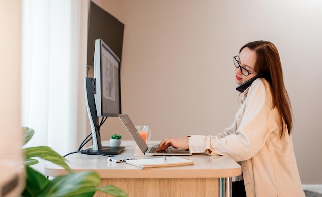 Femme d'affaires travaillant au bureau à domicile sur un ordinateur portable et parlant au téléphone avec des clients Jeune étudiante heureuse étudiant à l'université en ligne