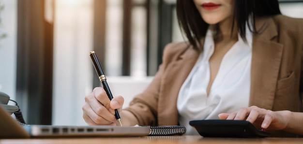 Femme d'affaires travaillant sur un bureau à l'aide d'une calculatrice pour calculer le concept de comptabilité financière des nombres