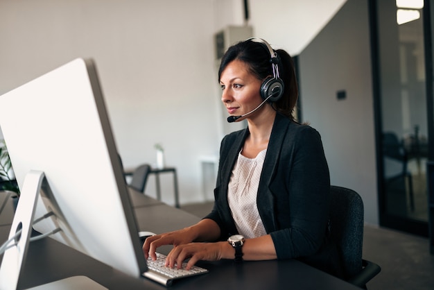 Femme d&#39;affaires travaillant avec le casque sur l&#39;ordinateur.