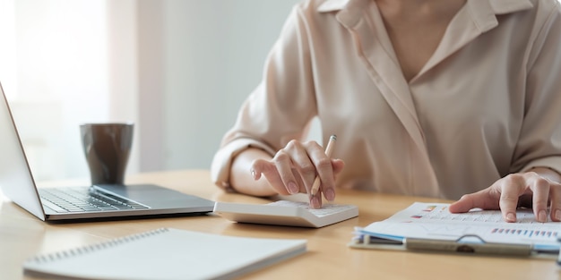 Femme d'affaires travaillant dans la finance et la comptabilité Analyser le budget financier avec une calculatrice et un ordinateur portable au bureau