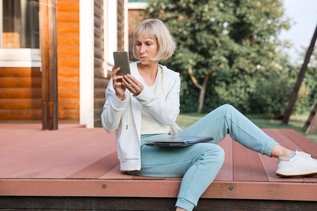 Femme d'affaires travaillant dans un parc avec téléphone et ordinateur portable