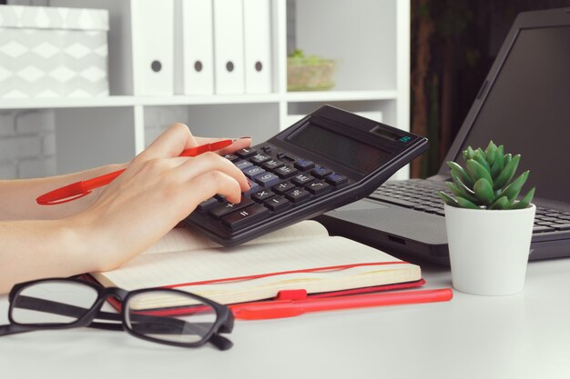 Femme d'affaires travaillant avec des données financières à la main à l'aide de la calculatrice