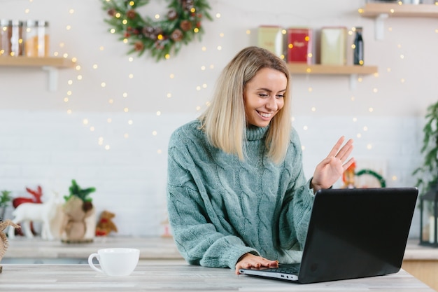 Femme d'affaires travaillant à la maison sur un ordinateur portable à Noël et au Nouvel An, heureuse et réussie de passer un appel vidéo à des collègues et amis