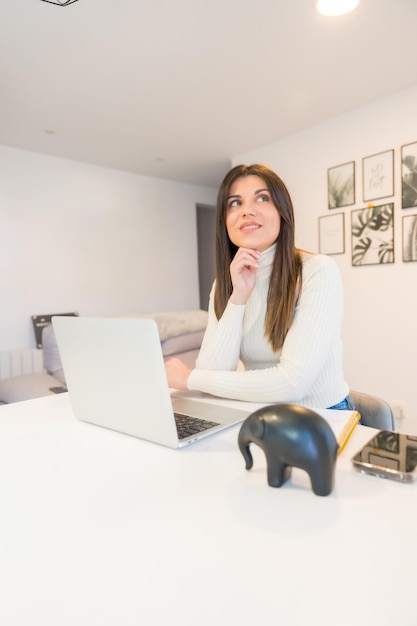 Femme d'affaires travaillant avec un ordinateur assis à la maison une entreprise réfléchie par le biais du télétravail au bureau à domicile