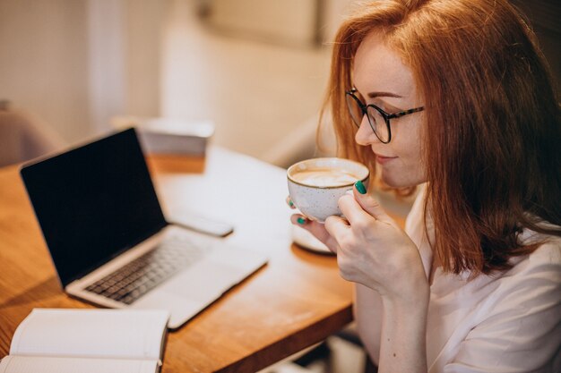 Femme d'affaires travaillant sur ordinateur dans un café et buvant du café