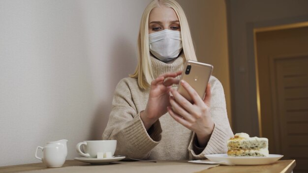 Femme d'affaires travaillant sur un ordinateur portable dans un café dans un masque médical, supprime. Suppression des mesures de quarantaine.