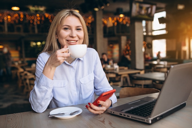 Femme d&#39;affaires travaillant sur ordinateur portable et téléphone dans un café