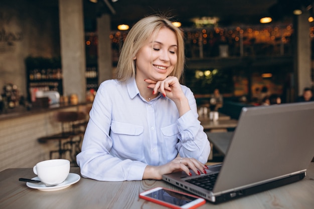 Femme d&#39;affaires travaillant sur ordinateur portable et téléphone dans un café