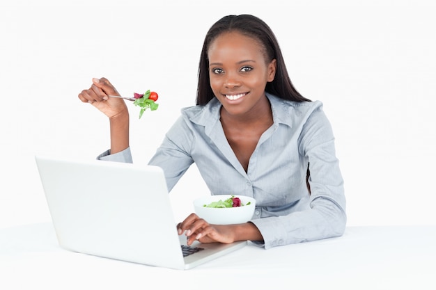 Femme d&#39;affaires travaillant avec un ordinateur portable tout en mangeant une salade