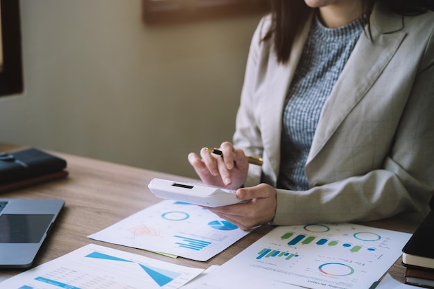 Femme d'affaires travaillant en tenant un stylo et en utilisant une calculatrice pour calculer le nombre d'électricité statique au bureau à domicile Concept de comptabilité financière