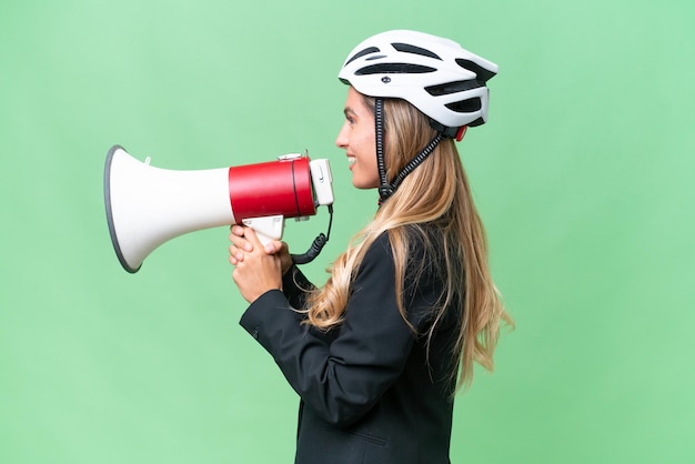 Femme d'affaires uruguayenne portant un casque biker sur fond isolé criant à travers un mégaphone