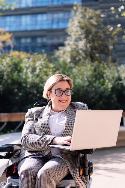 Femme d'affaires utilisant un fauteuil roulant travaillant avec un ordinateur