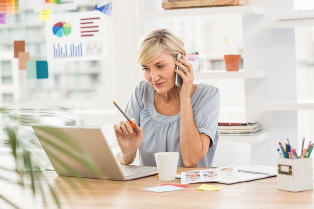 Femme d&#39;affaires utilisant un ordinateur portable au téléphone