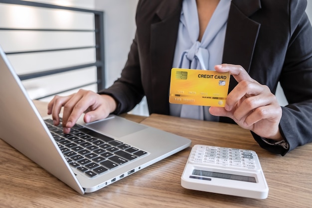 Une femme d'affaires utilisant un ordinateur portable et détenant une carte de crédit pour payer la page de détail affiche les achats en ligne et le code de sécurité d'entrée pour saisir les informations de la carte.