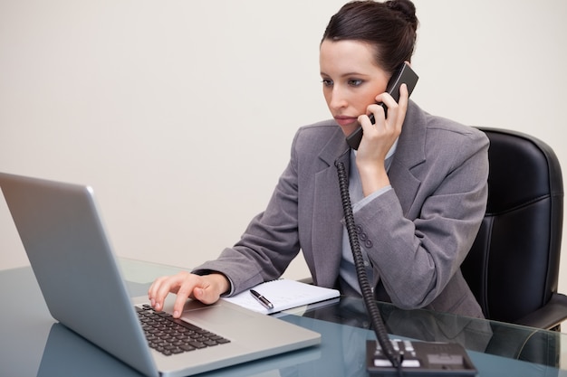 Femme d&#39;affaires utilisant un ordinateur portable pendant un appel