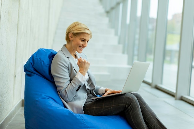 Femme d'affaires utilisant un ordinateur portable sur un sac paresseux dans le bureau moderne