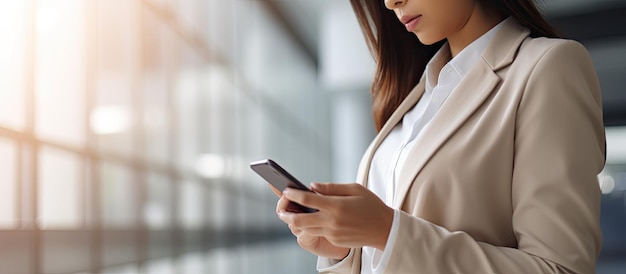 Femme d'affaires utilisant un smartphone naviguant sur Internet à l'écran dans un bureau moderne représentant le concept de données ou de réseaux sociaux