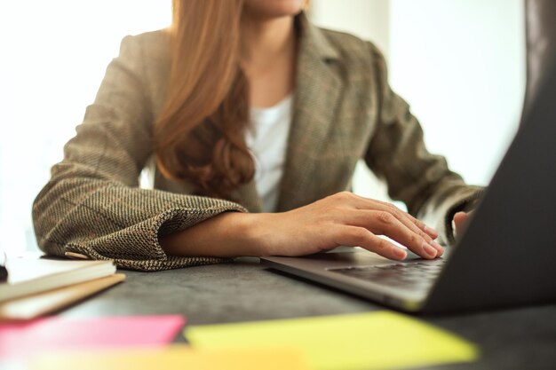 Femme d'affaires utilisant et tapant sur un ordinateur portable avec des documents sur la table au bureau