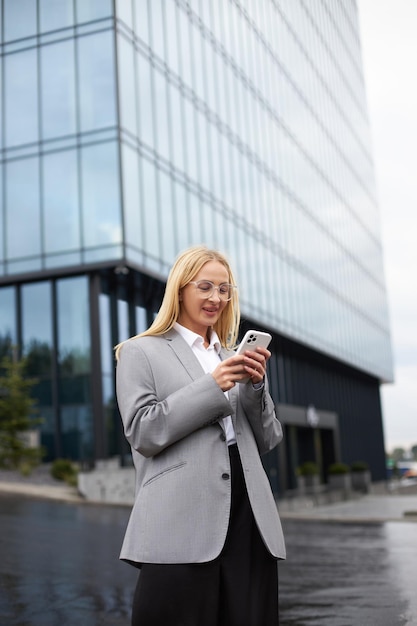Femme d'affaires utilisant un téléphone portable lisant un message texte vérifier la communication par e-mail en ligne dans la rue