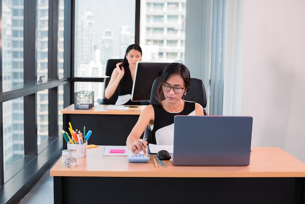 Une femme d'affaires utilise une calculatrice dans un bureau moderne