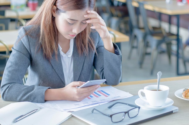 Une femme d'affaires utilise un téléphone portable mécontent dans un café